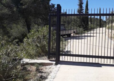 Construcción de puerta y cercado, para una casa de montaña, formada por hierro galvanizado